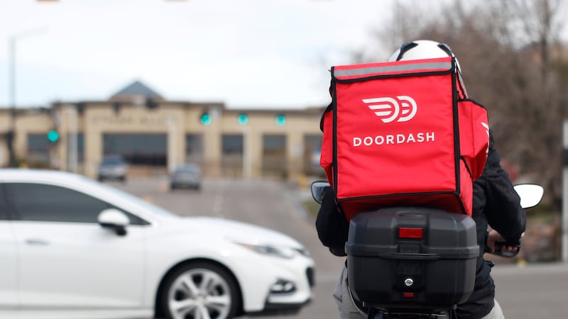 FILE - A food delivery motorcycle rider waits for the traffic light to change March 30, 2020,...
