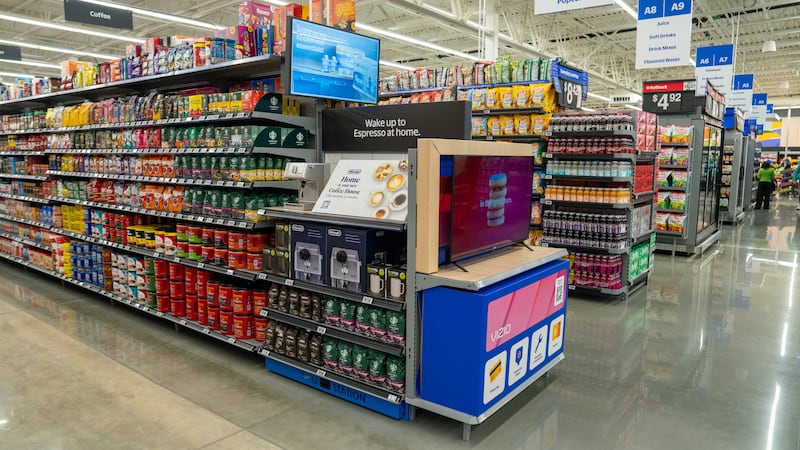 A brightly lit Walmart aisle features shelves a prominent Espresso machine display, a Vizio...