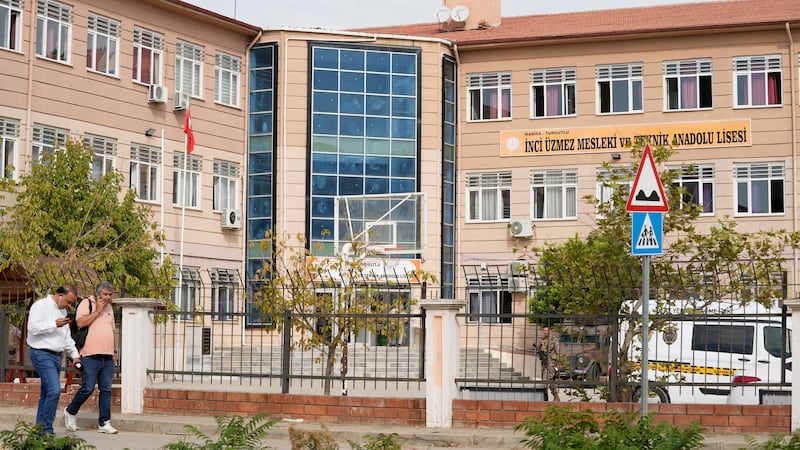 Gente camina junto a una escuela secundaria y profesional en el distrito Turgutlu en la...