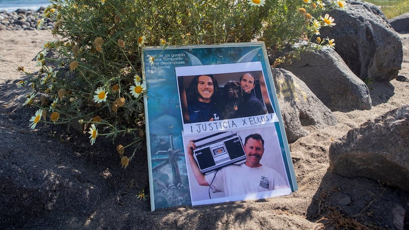 FILE - The photos of foreign surfers who disappeared are displayed on a poster on the beach in...