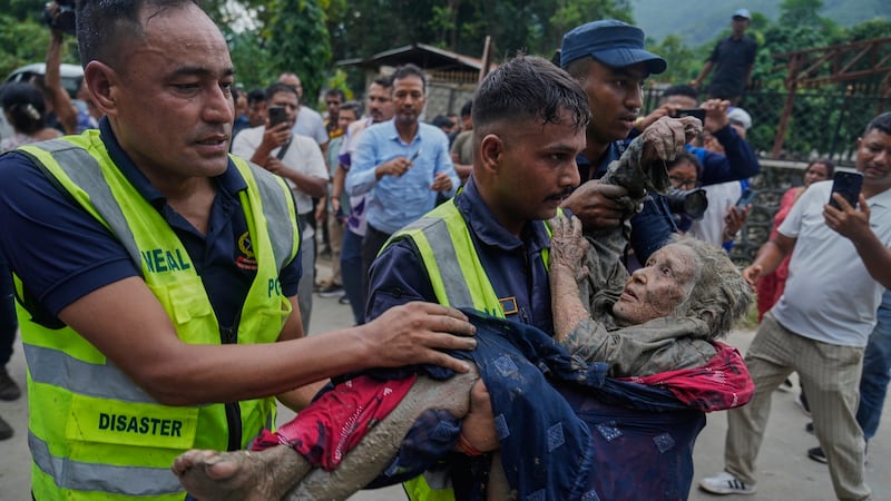 Rescuers carry a victim of flash flooding to safety along the Trishuli River in Nepal's...